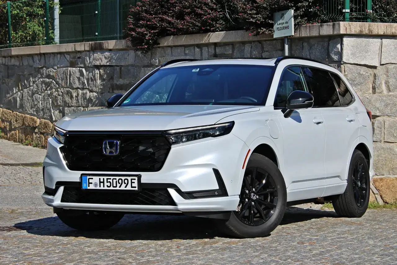 Nowy Honda CR-V 2.0 benzyna, biały SUV z czarnymi felgami, zaparkowany na brukowanej ulicy przy kamiennym murze.