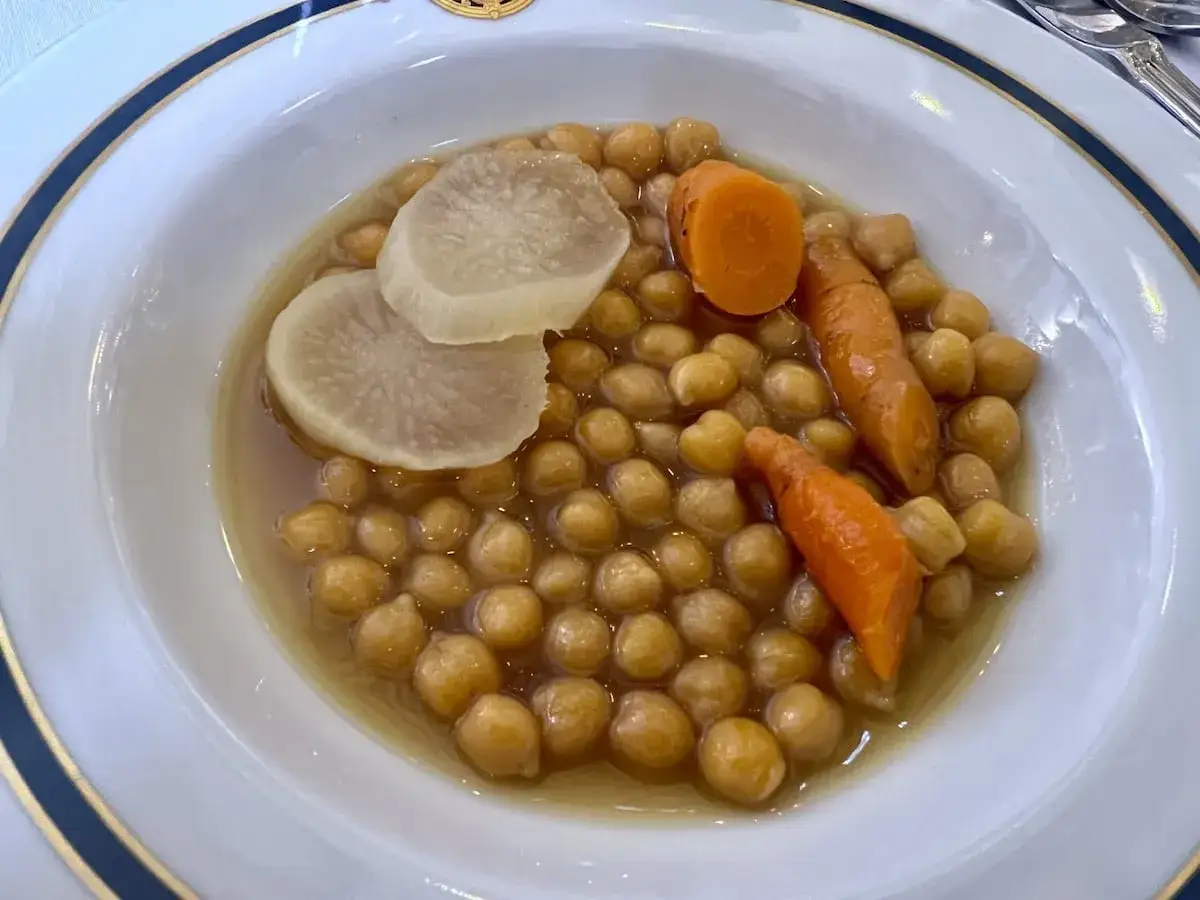 Un plato de garbanzos con zanahorias y rodajas de nabo, un delicioso plato de olla podrida.