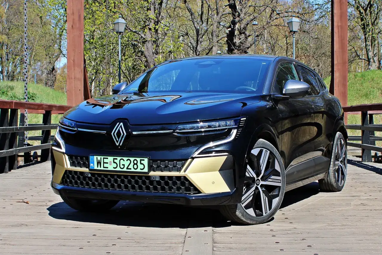 Elegancki, czarny Renault Megane E-Tech na drewnianym moście, z detalami w kolorze złota i nowoczesnymi światłami.