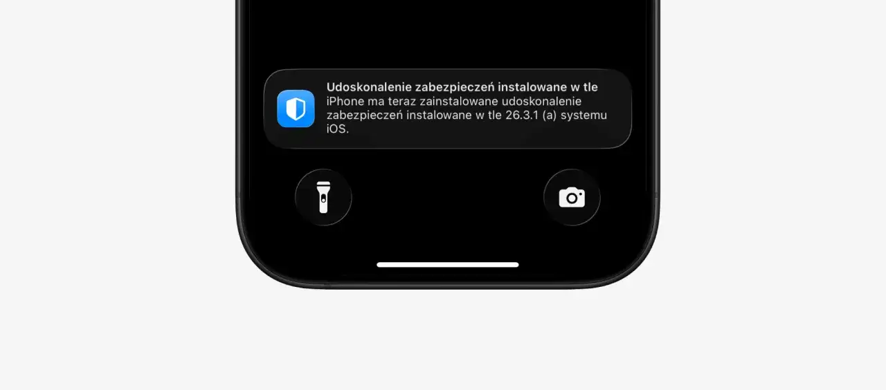 iPhone z iOS 26.4.1 (a) informuje o zainstalowaniu udoskonalenia zabezpieczeń w tle. Widoczne ikony latarki i aparatu.