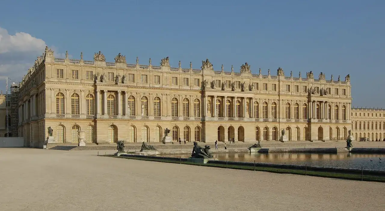 Le château de Versailles, construit par Louis XIV, s'étend majestueusement avec ses façades dorées et ses bassins réfléchissants.