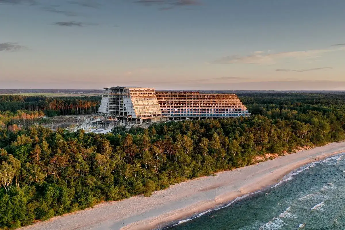 Budowa największego hotelu nad morzem, otoczonego lasem, z widokiem na plażę i morze o zachodzie słońca.
