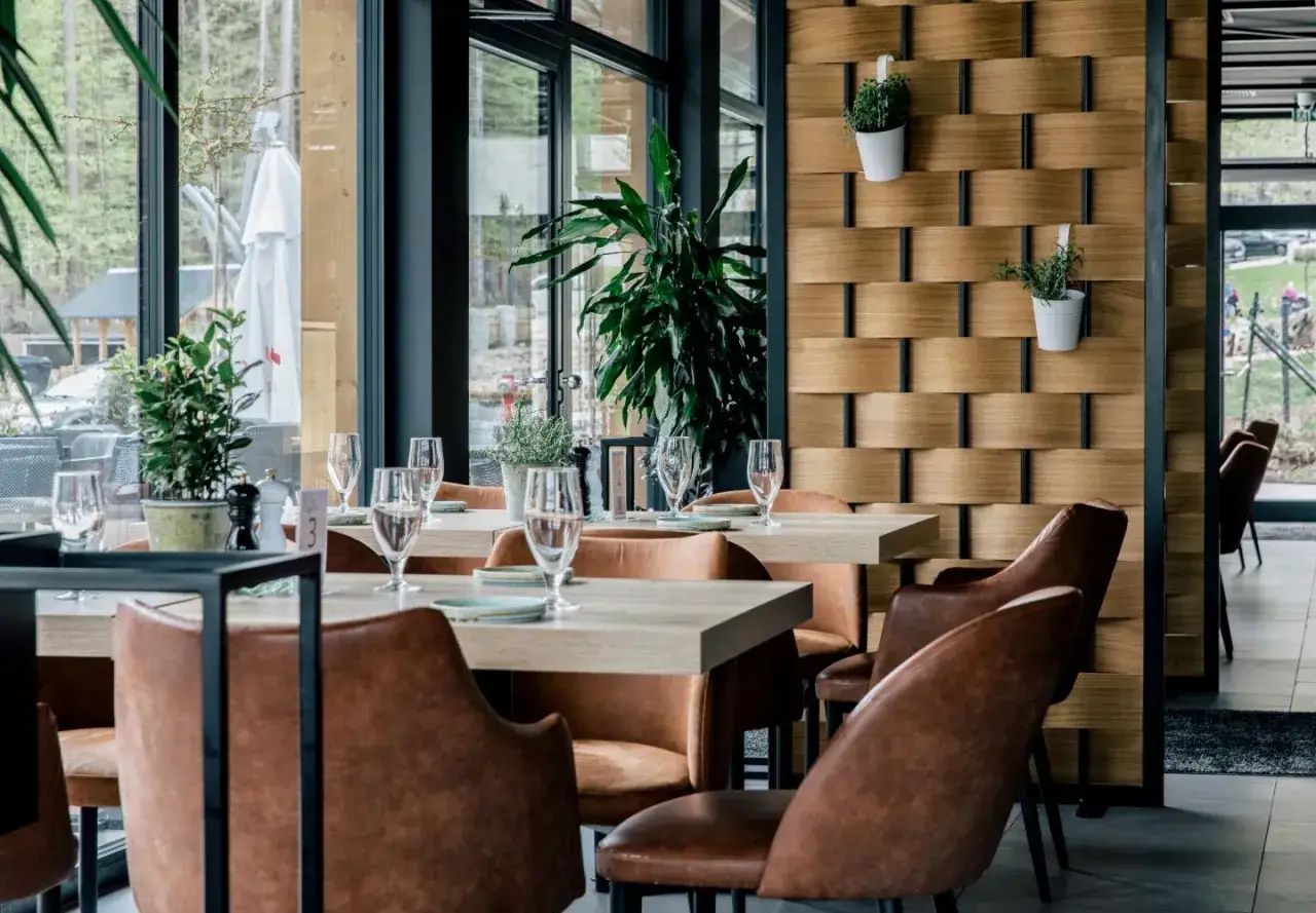Eleganckie wnętrze restauracji w Szklarskiej Porębie. Drewniane panele, wygodne fotele i stoły nakryte do kolacji.