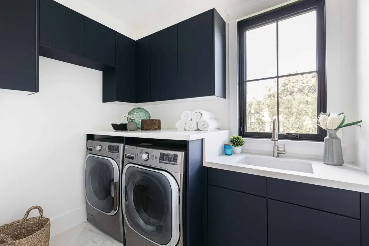 Linge propre et rang&eacute; dans cette buanderie moderne. La profondeur des meubles sombres met en valeur les machines &agrave; laver.