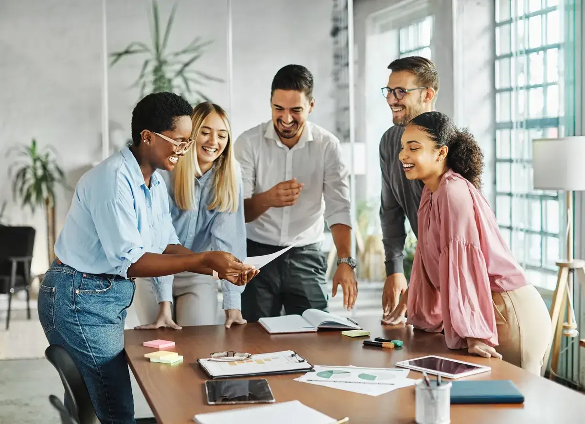Une équipe souriante autour d'une table, partageant des documents. Un vrai levier de motivation pour ce projet !