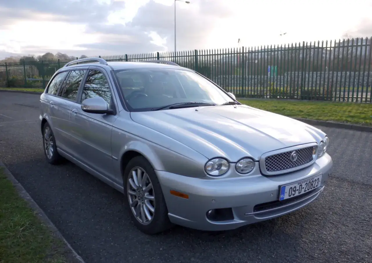 Srebrny Jaguar X-Type kombi stoi na poboczu drogi.
