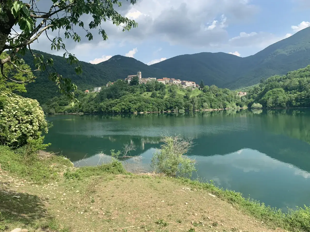 Vue paisible du lago di vagli, avec un village perché sur une colline verdoyante.