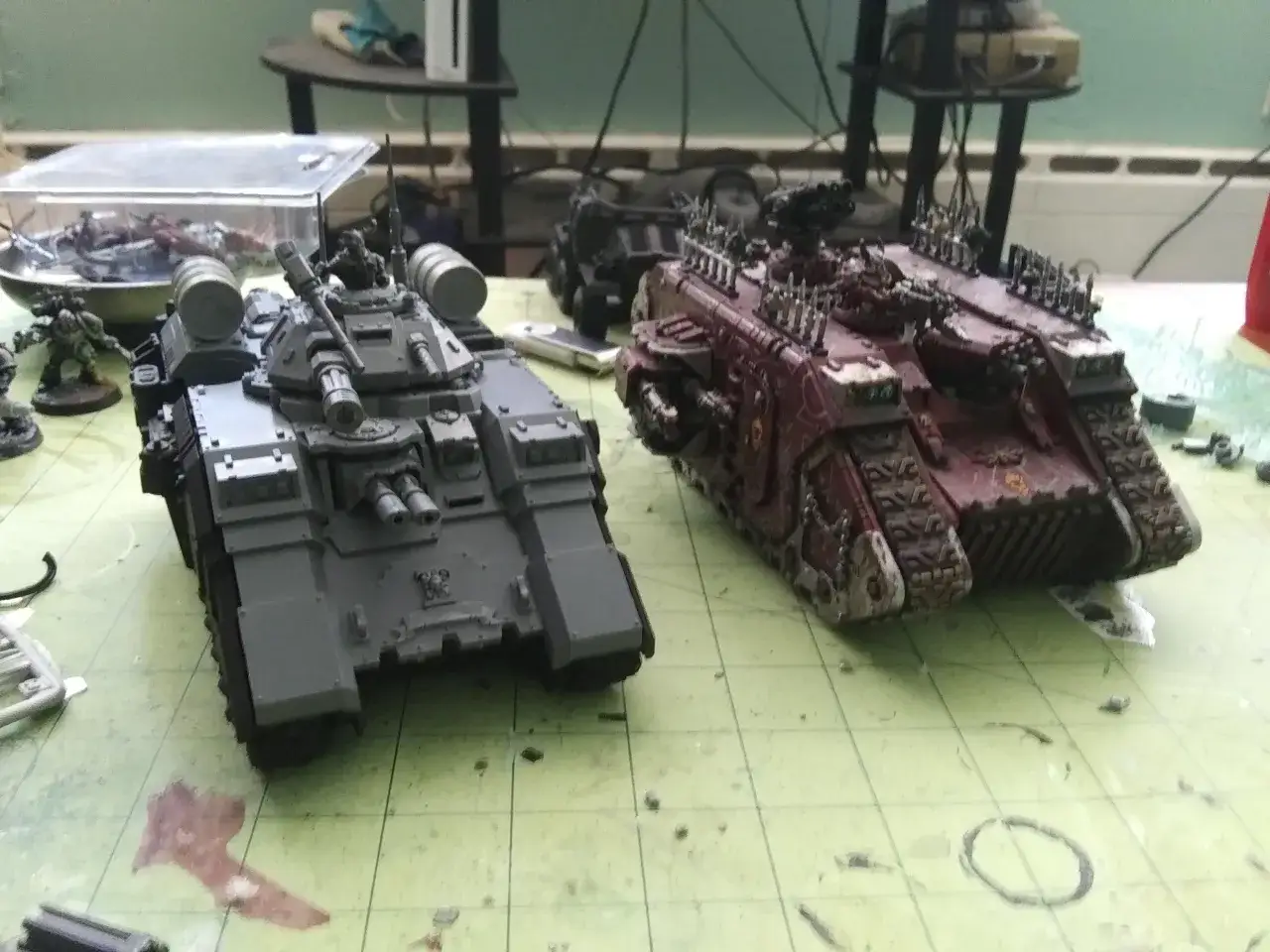 Dwa modele pojazdów, jeden szary, drugi czerwony, przypominają czołgi Land Raider Redeemer.
