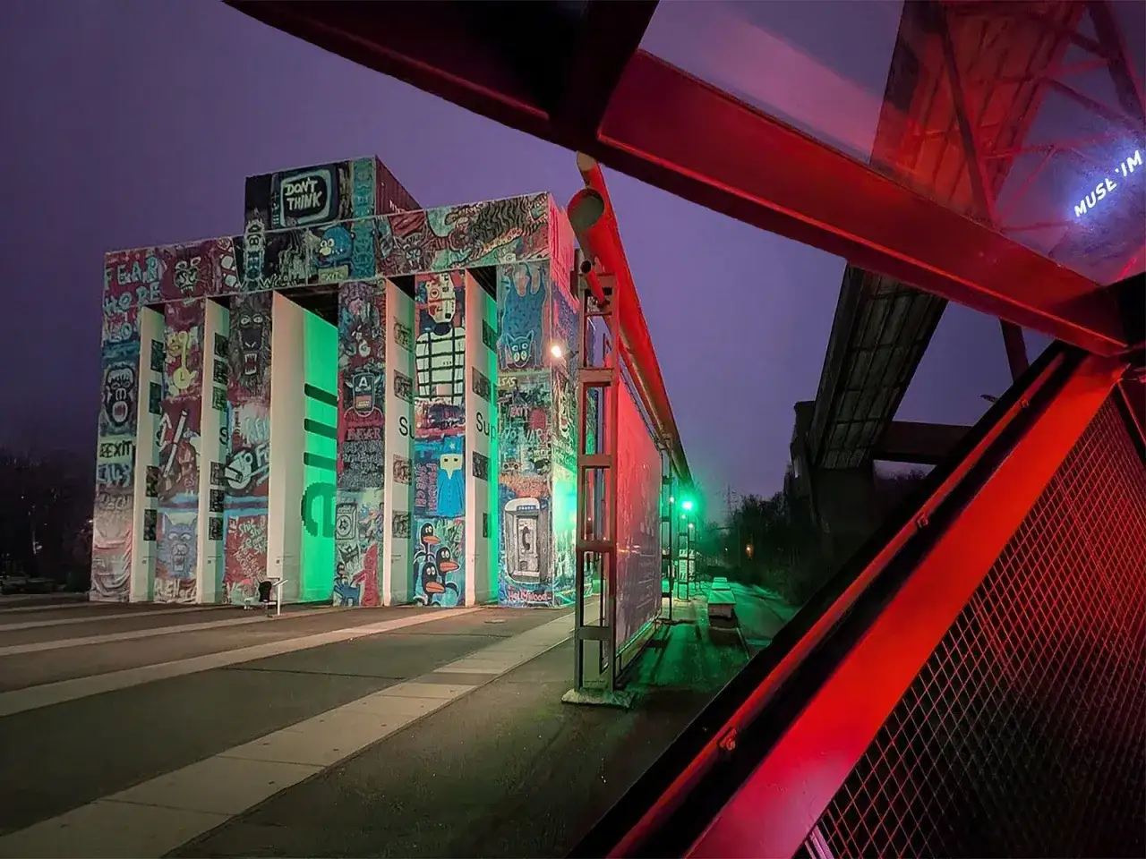 Bunte Graffiti-Kunst erhellt die **Zeche Zollverein** in der Nacht. Grüne und rote Lichter tauchen die Szenerie in ein mystisches Licht.