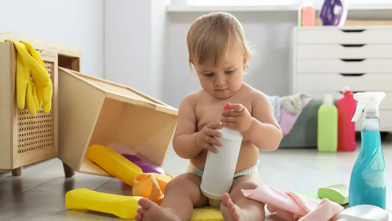 Kleines Kind spielt mit Reinigungsmitteln. Vorsicht vor eukalyptus vergiftung symptome, wenn Kinder Zugang zu solchen Mitteln haben.