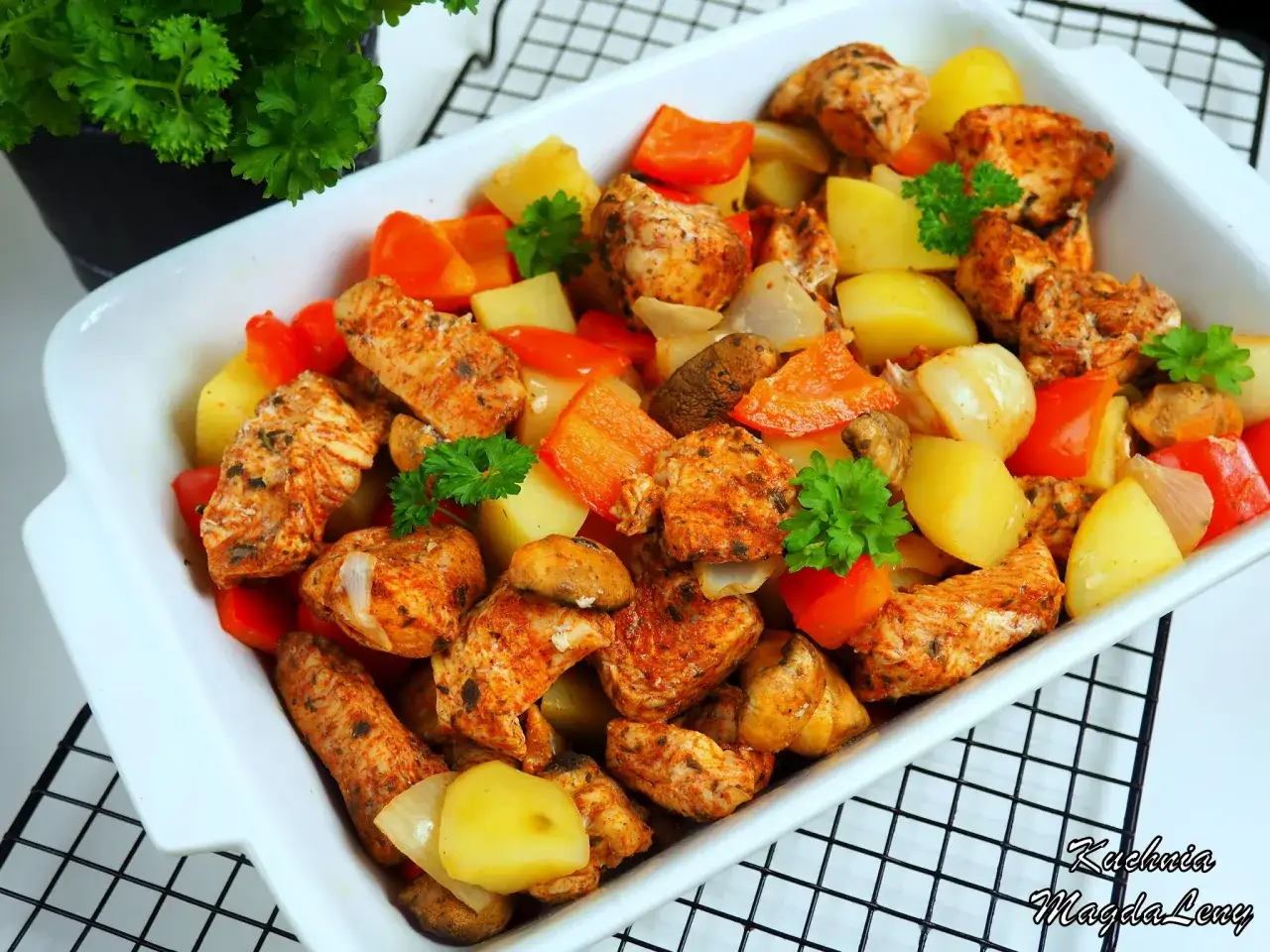 Pyszny filet z indyka pieczony w rękawie z ziemniakami, papryką i cebulą, udekorowany natką pietruszki.