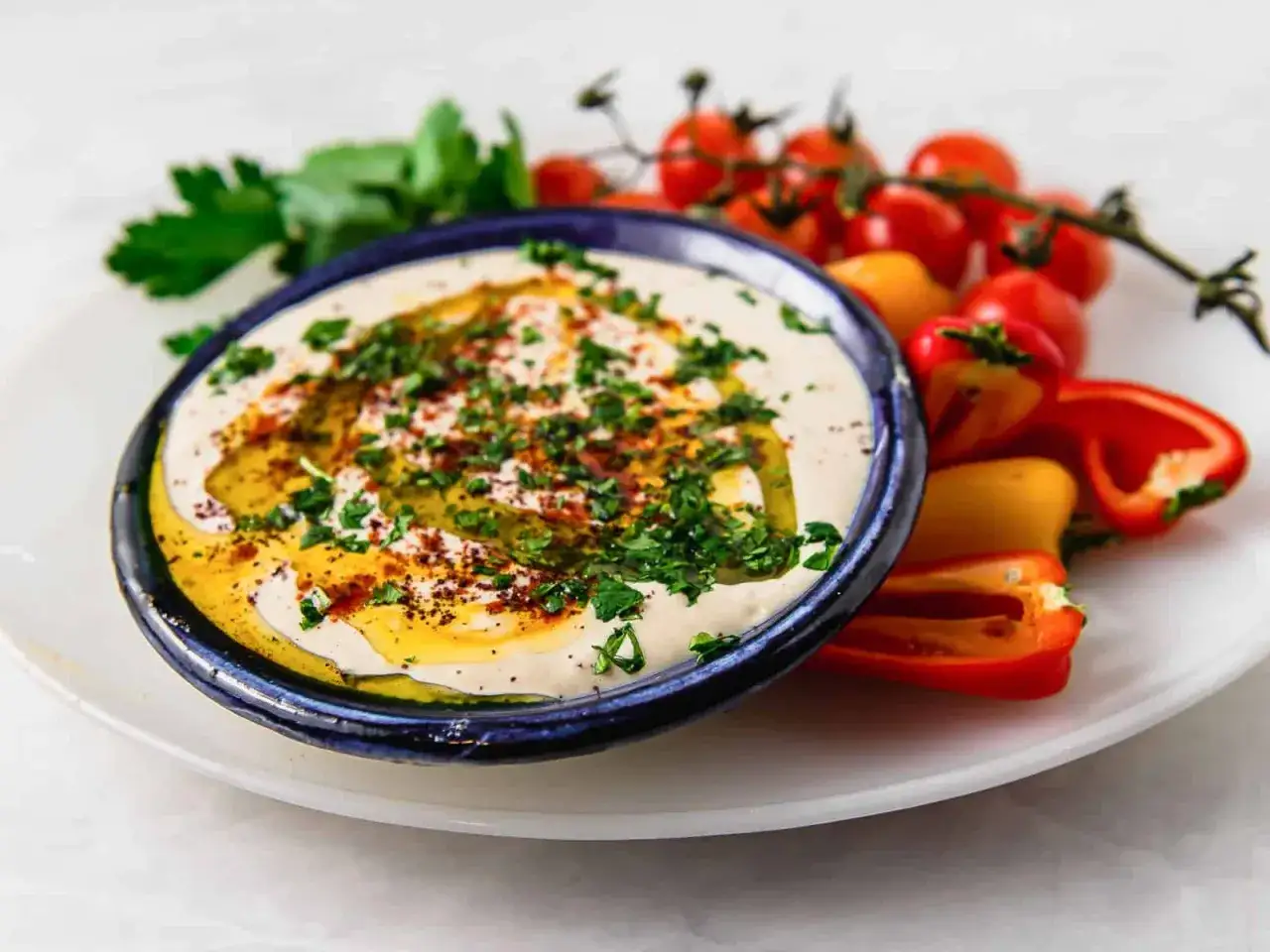 Krämig hummus med olivolja, persilja och paprika. Ett perfekt tahini recept för dippning.