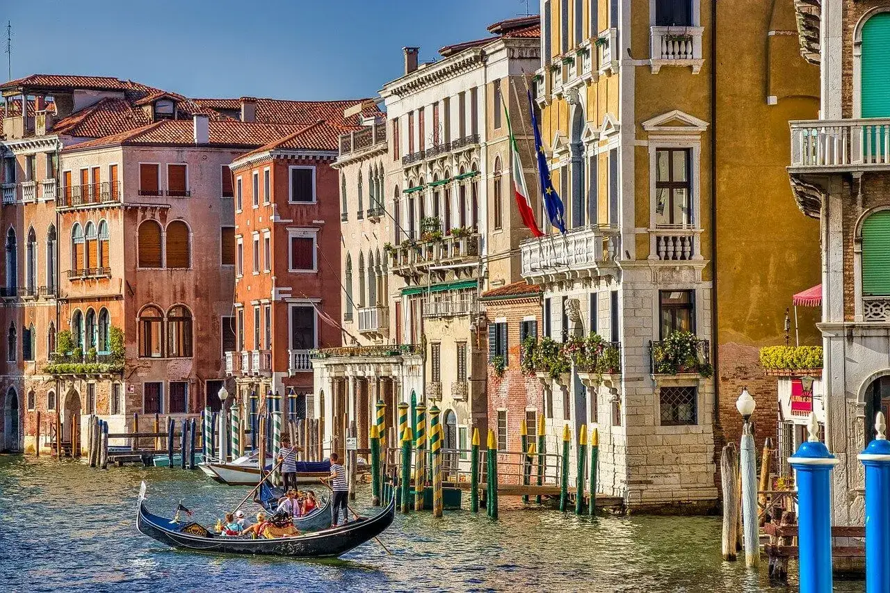 Wiosenna, słoneczna Wenecja w kwietniu. Gondola płynie po Canale Grande, mijając kolorowe kamienice i ozdobne pale.