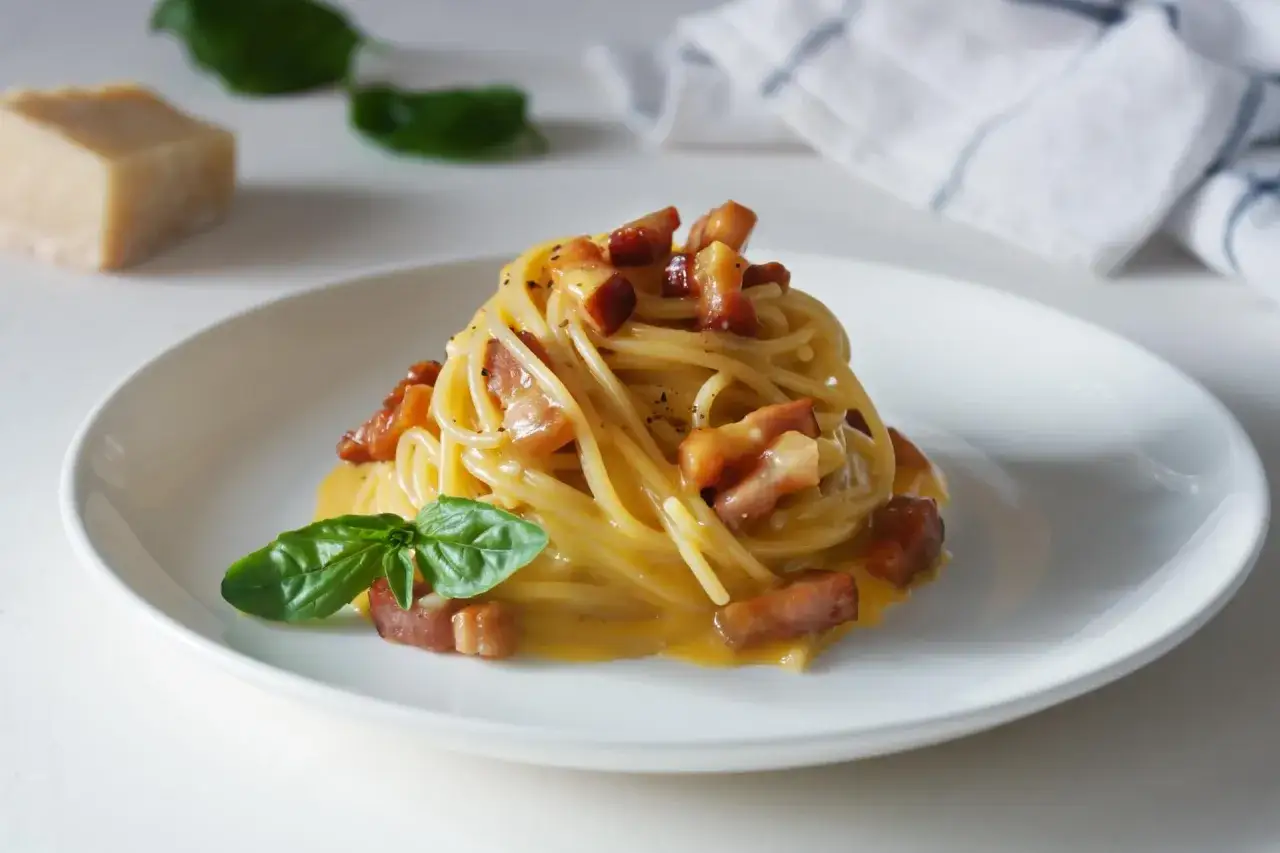 Pyszna carbonara z boczkiem i bazylią. Jaki ser do carbonary? Najlepszy jest parmezan, który widać obok dania.