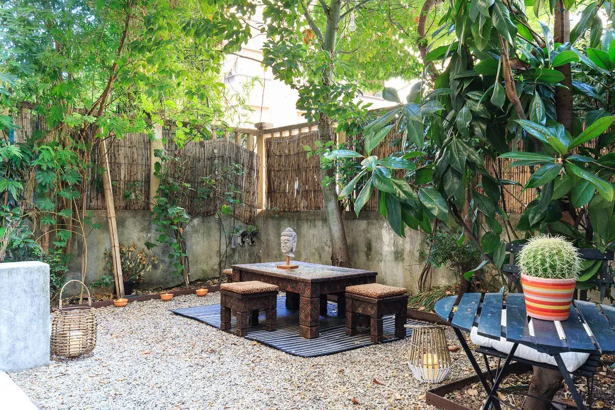 Un angolo relax per il tuo progetto giardino 50 mq: tavolino intagliato, sgabelli, lanterne e un cactus colorato.
