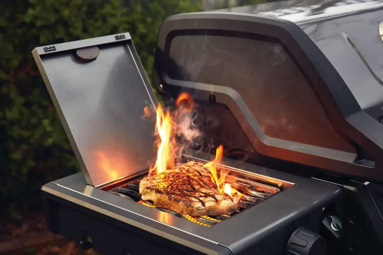 Ein saftiges Steak brutzelt in der Sizzle Zone auf einem Grill, Flammen lodern.
