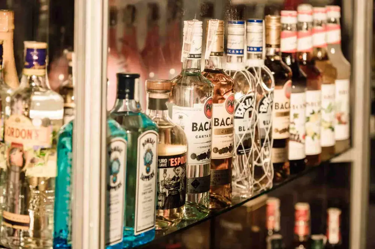 Jak zaplanować bar tematyczny z wódkami świata na event? Rząd butelek Bacardi i innych alkoholi na półce.
