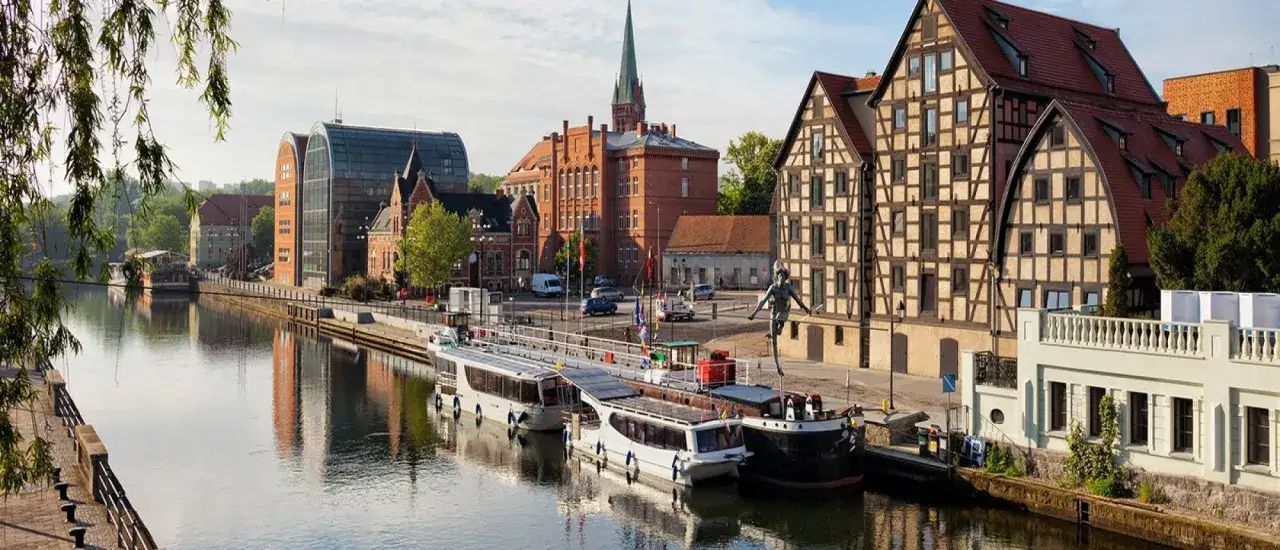 Bydgoszcz atrakcje: malowniczy widok na Brdę z łodziami, zabytkowe kamienice i nowoczesne budynki tworzą niepowtarzalny klimat.
