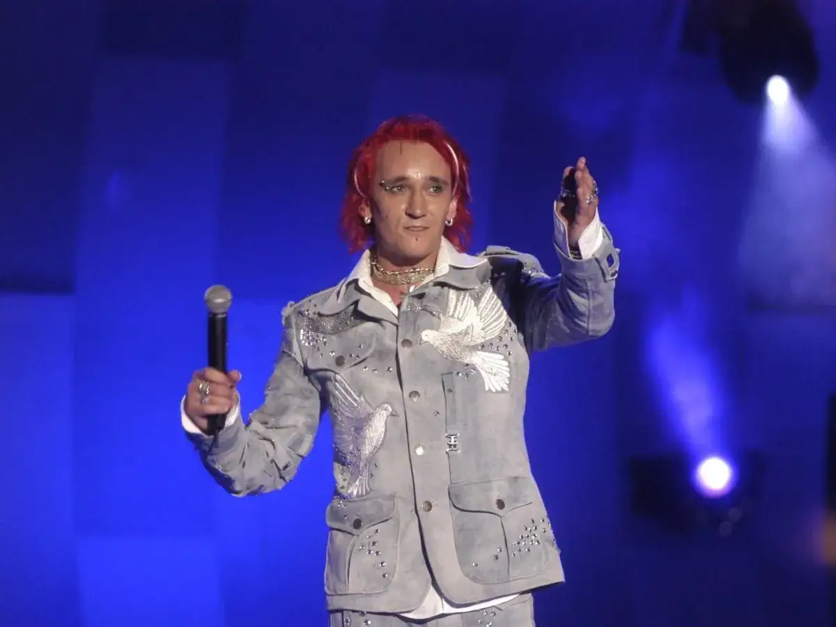 Michał Wiśniewski, z charakterystycznymi rudymi włosami i w ozdobnej kurtce z gołębiami, śpiewa na scenie. Ile lat ma Michał Wiśniewski?