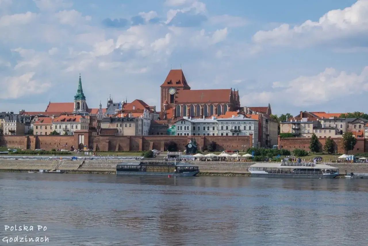 Widok na zabytkowe Stare Miasto w Toruniu, wpisane na listę UNESCO Polska, z ceglanymi murami obronnymi i katedrą.