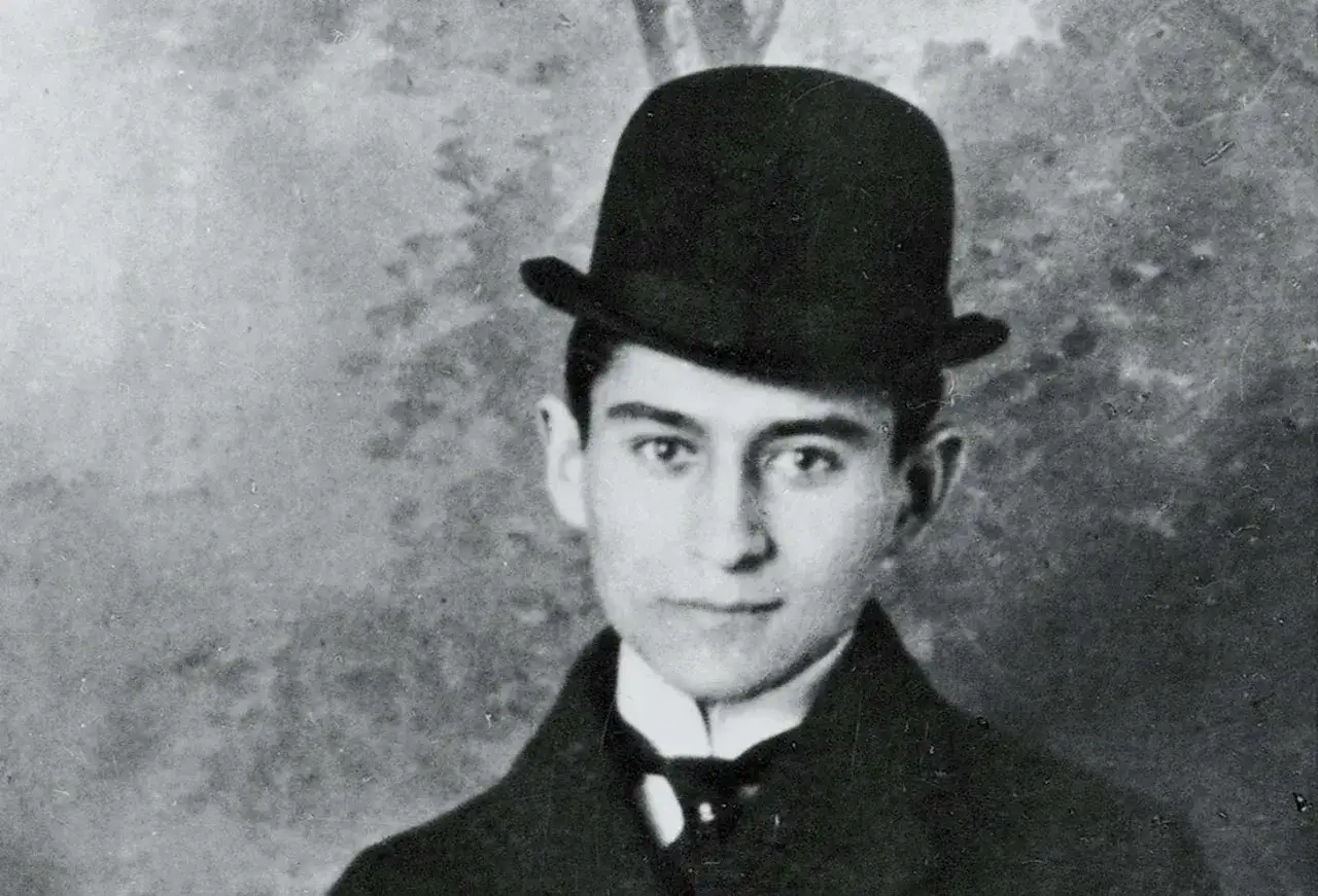 Młody Franz Kafka w meloniku i eleganckim stroju, zamyślony wzrok.
