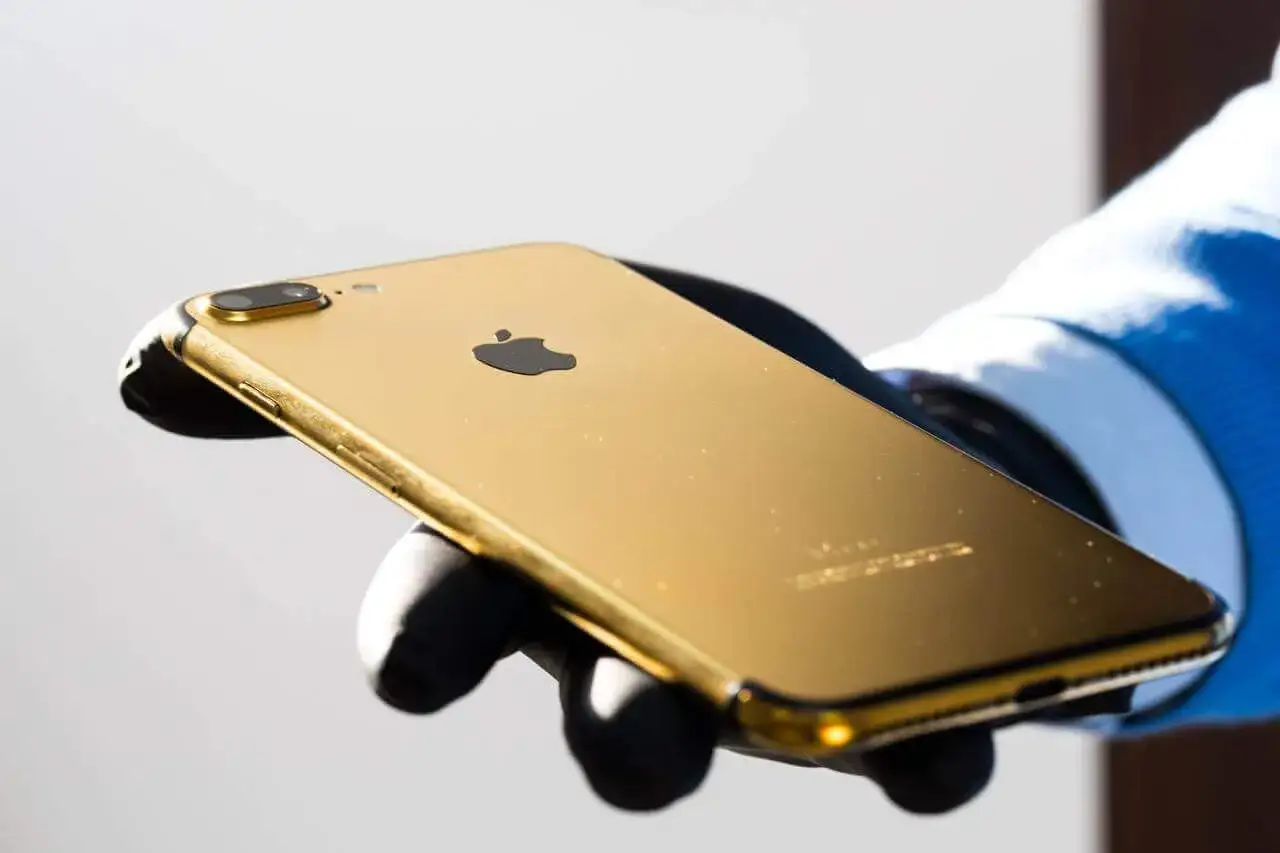 Złoty iPhone X w dłoni, lśniący jak skarb.
