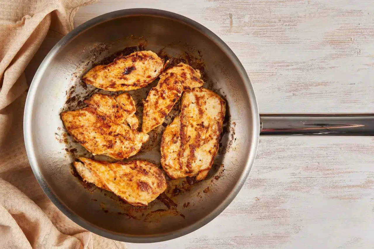 Po&ecirc;le en acier inoxydable avec des morceaux de poulet grill&eacute;s. Attention, la chaleur du po&ecirc;le en acier inoxydable peut &ecirc;tre un danger.