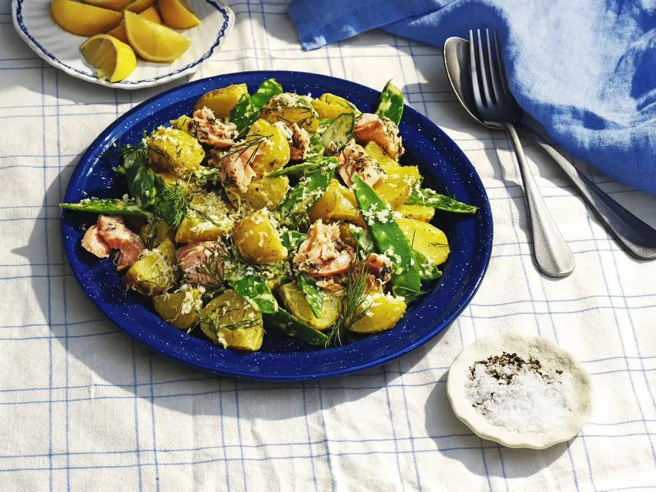 En härlig potatissallad till lax, med färsk dill och gröna bönor, serverad på en blå tallrik.
