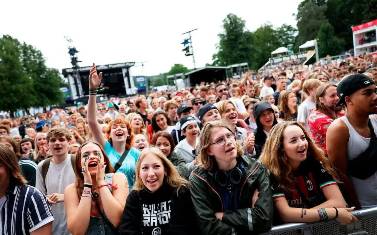 Publiken jublar p&aring; en konsert, kanske f&ouml;r att se sina favorit svenska rappare. M&aring;nga unga m&auml;nniskor njuter av musiken och st&auml;mningen.