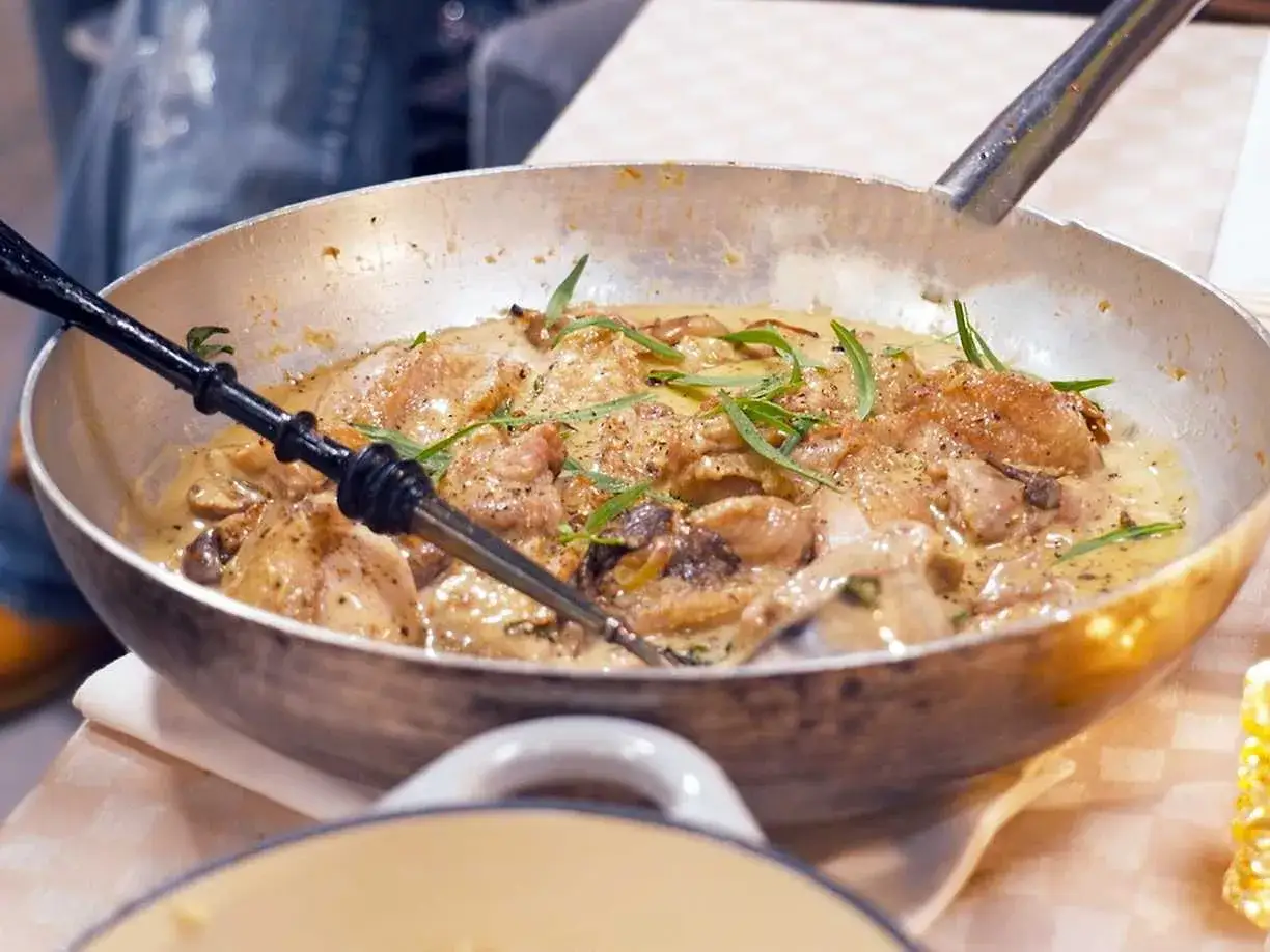 En panna med kr&auml;mig coq au vin blanc, kycklingbitar, svamp och &ouml;rter.