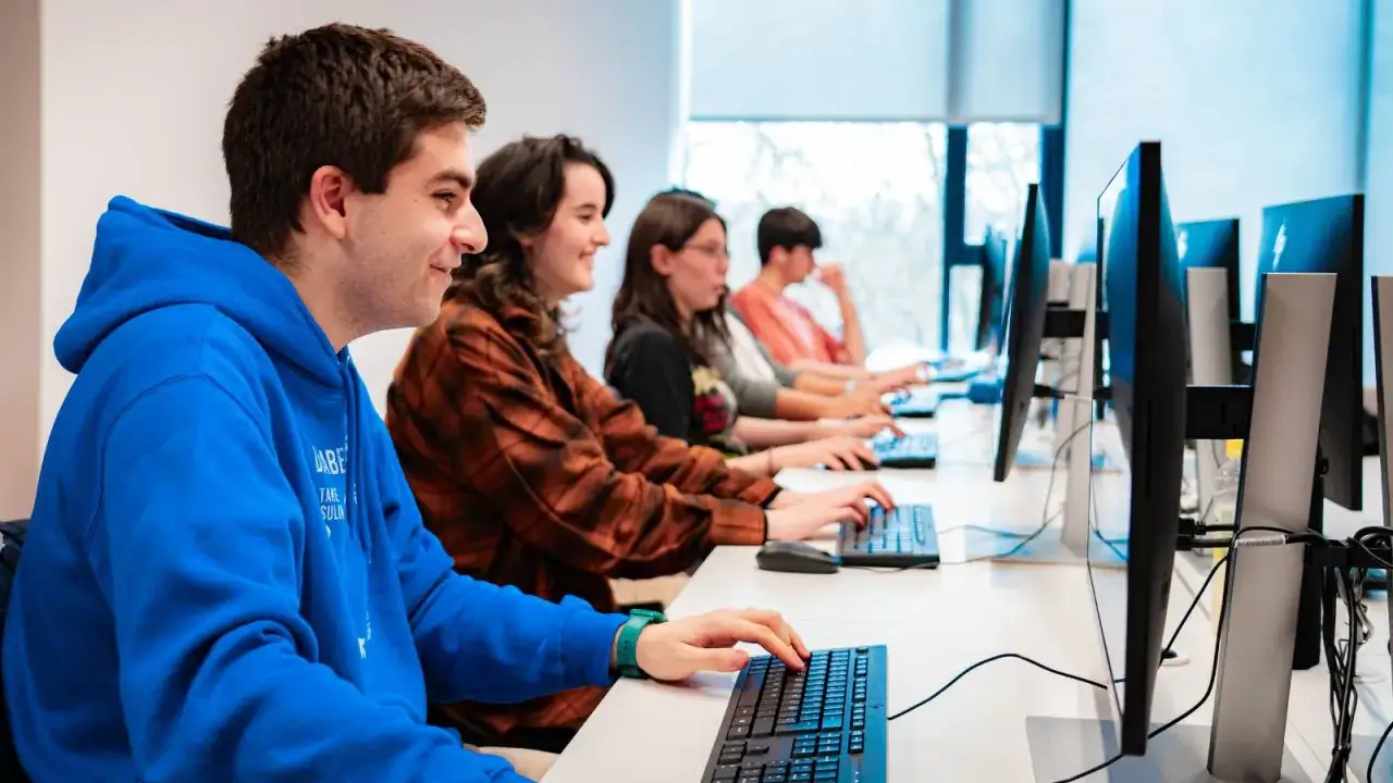Estudiantes concentrados en sus ordenadores, aprendiendo **fp online informatica**.