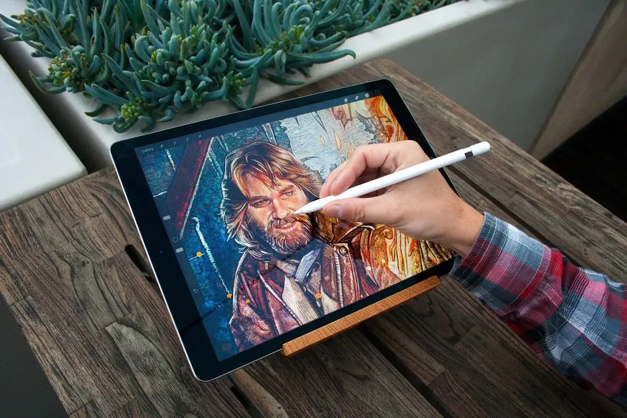 Main d'un artiste utilisant un stylet pour une formation en digital painting sur une tablette affichant un portrait détaillé.