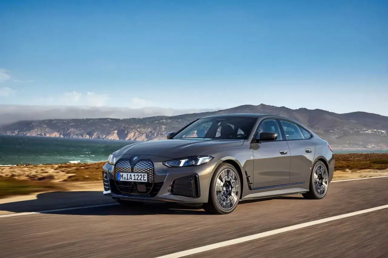 Grauer BMW i4 Facelift f&auml;hrt auf einer K&uuml;stenstra&szlig;e.