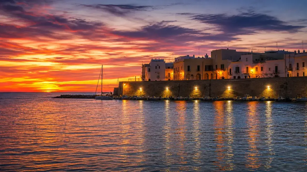 Tramonto infuocato su Gallipoli vecchia, con le luci che illuminano i vicoli e il porto.