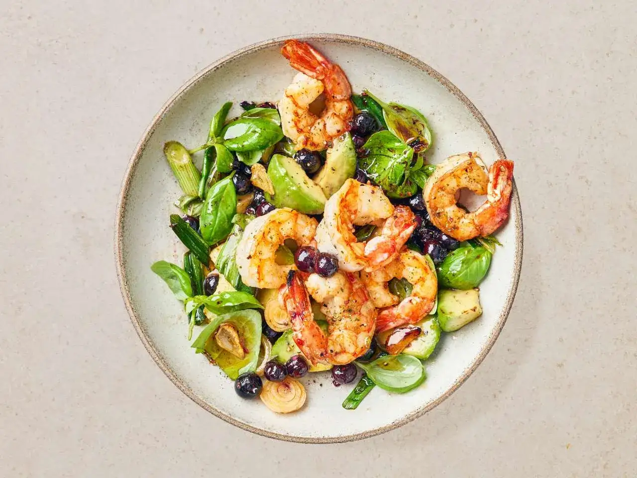 Schmackhafter Salat mit argentinische rotgarnelen, Avocado, Blaubeeren und grünen Blättern, garniert mit Kräutern.