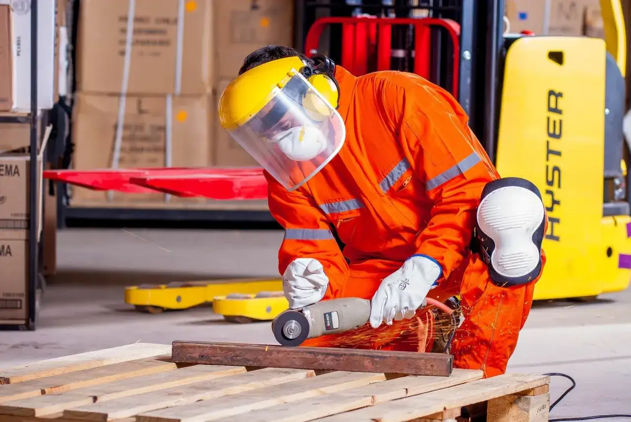Operaio con DPI completi, tra cui visiera e maschera, usa smerigliatrice. Il RSPP quando è obbligatorio garantisce la sicurezza in questi lavori.
