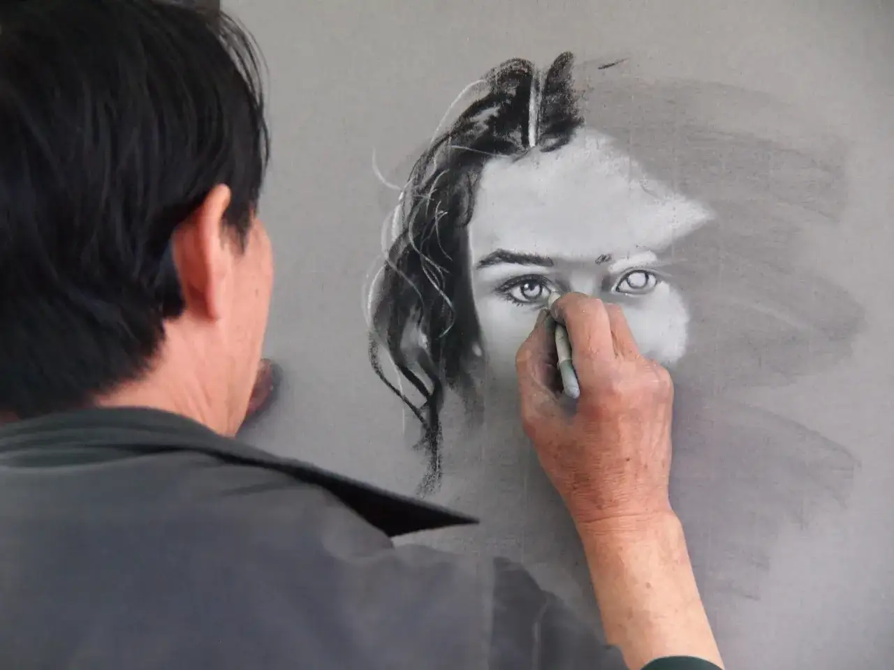 Artysta tworzy portret, używając węgla. R&oacute;żne rodzaje rysunku artystycznego ożywają pod jego ręką.