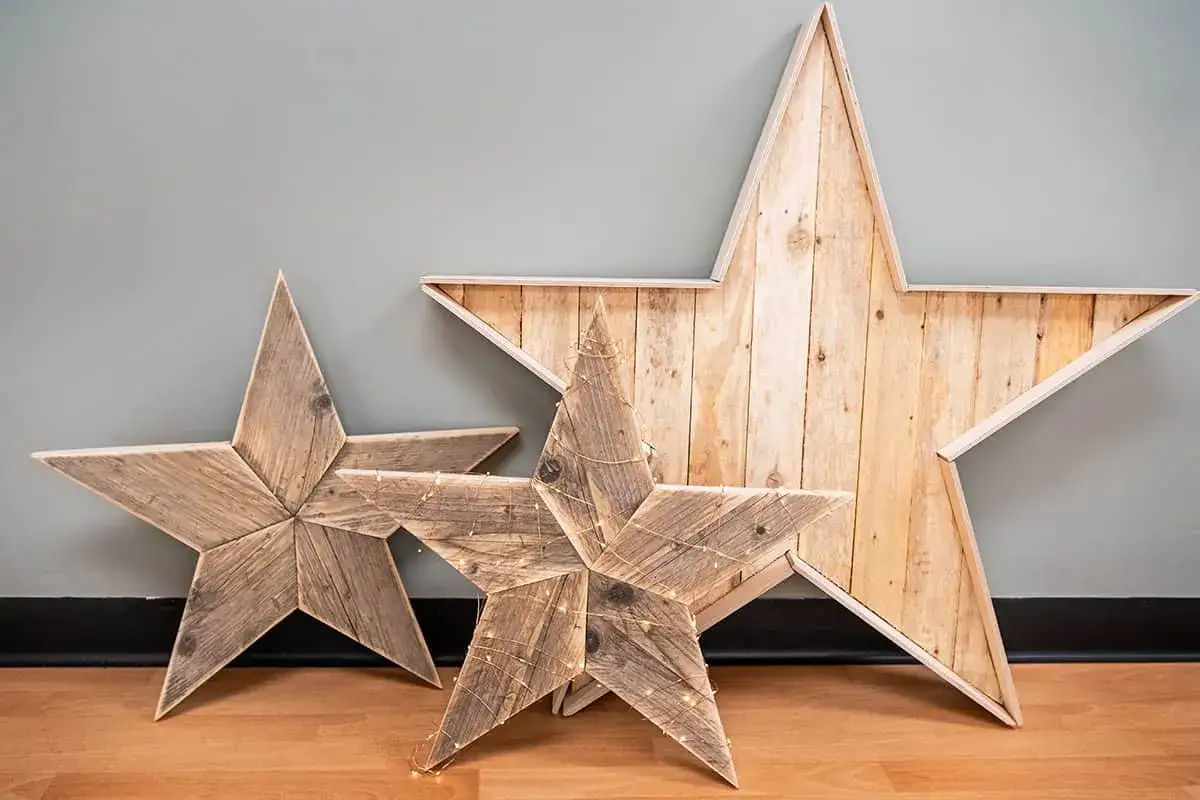 Idées pour que faire avec des vieilles planches de bois : trois étoiles décoratives en bois, dont une avec des guirlandes lumineuses.