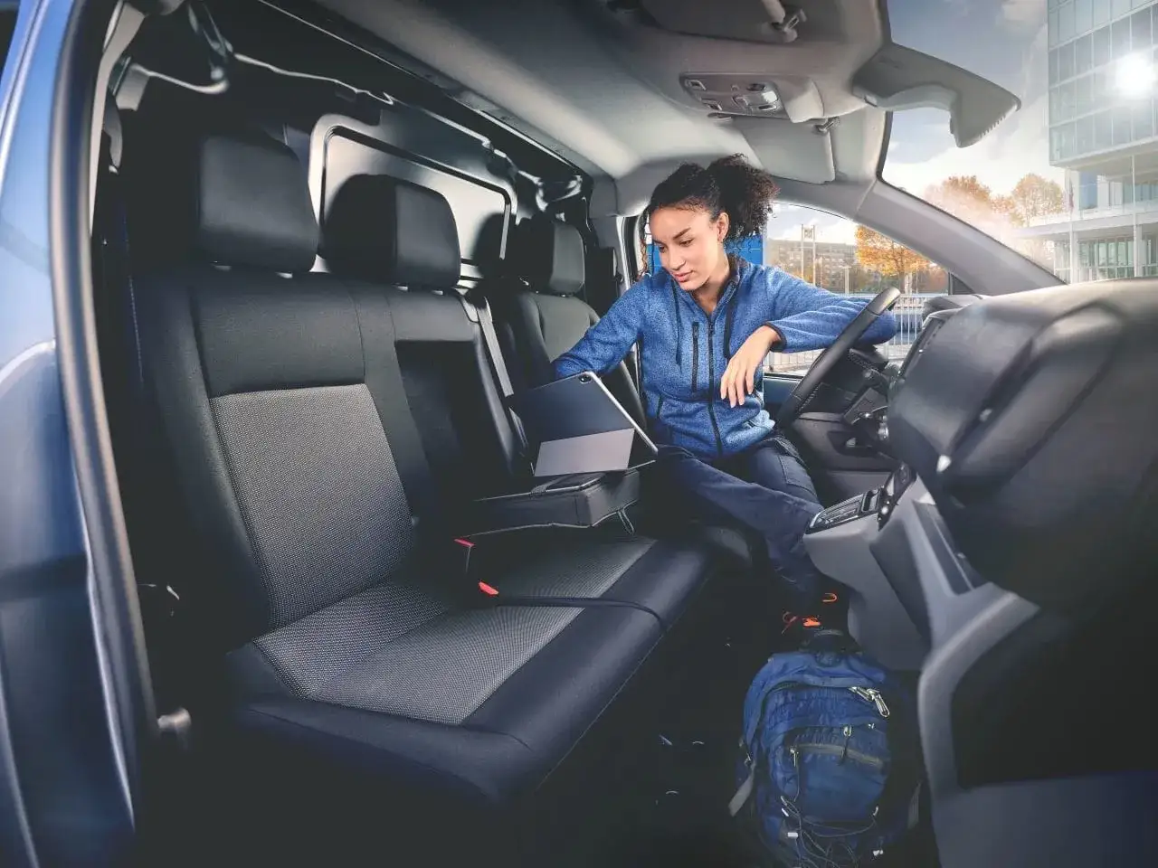 Interno di un doblo 9 posti. Una donna usa un tablet seduta sui sedili posteriori, pronta per un viaggio di lavoro.