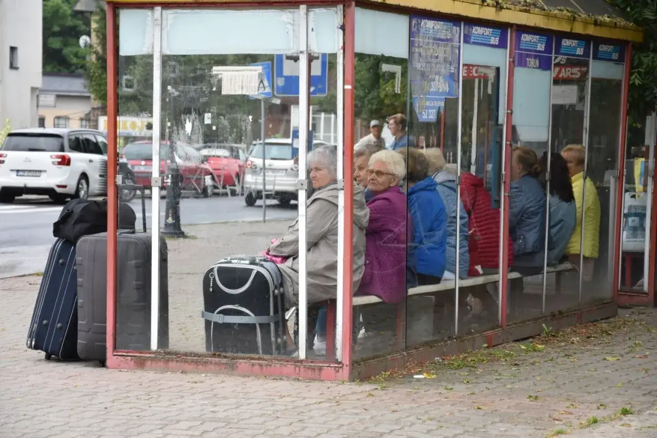 Grupa osób z walizkami czeka na busy do Ciechocinka.