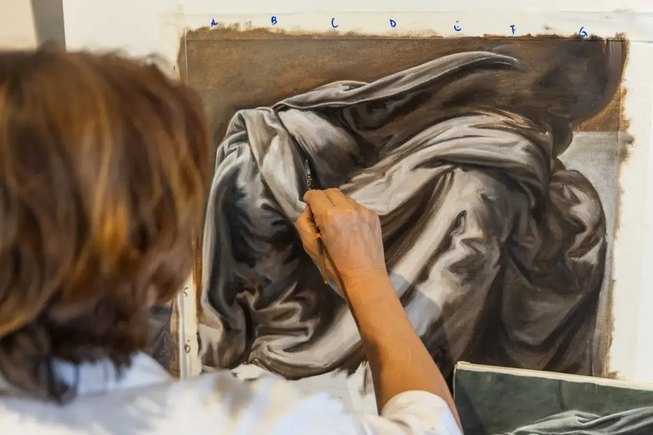 Un artiste travaille sur des modèles de drapés en peinture, capturant les jeux d'ombre et de lumière sur le tissu.