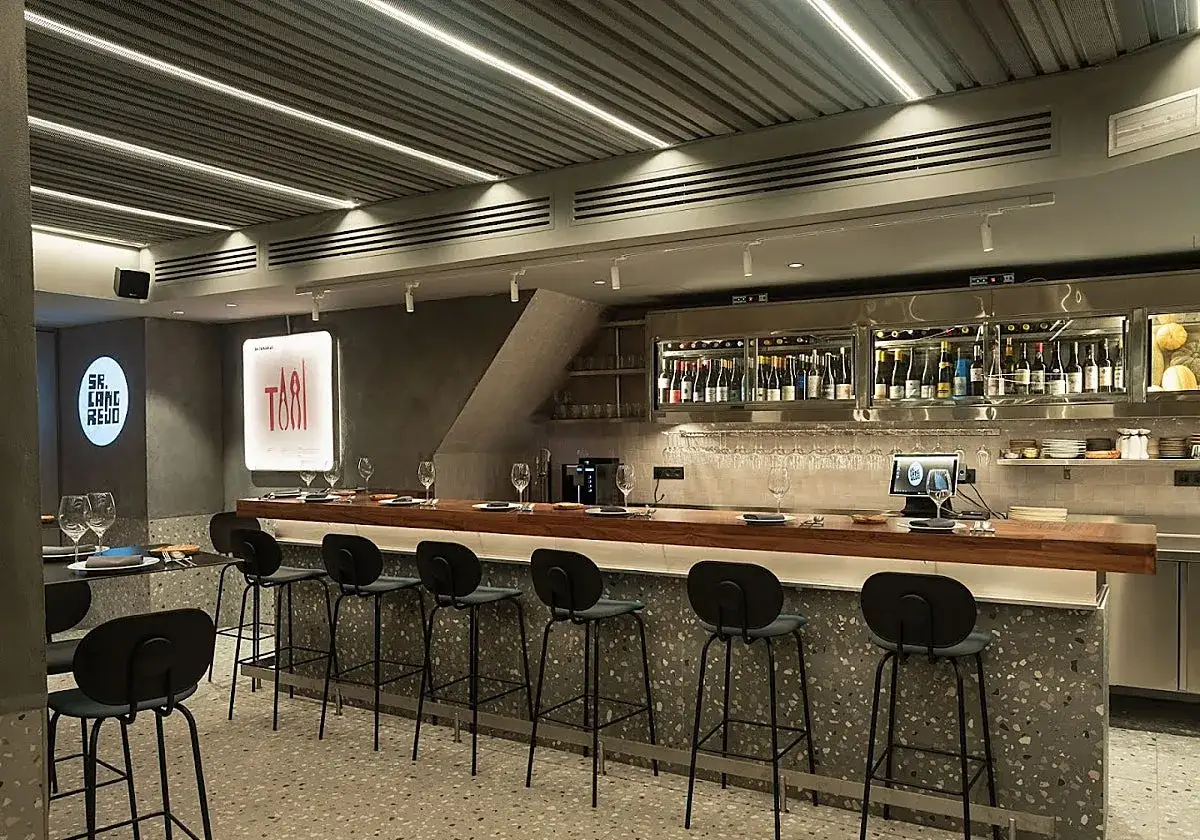 Interior moderno de un restaurante listo para abrir. Barra con taburetes, botellas de vino y luces LED.