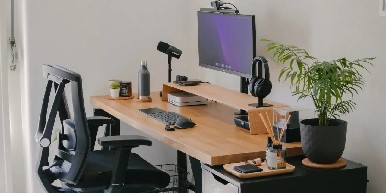 Un bureau bien organis&eacute; avec un ordinateur, un microphone, un casque, une plante et une chaise ergonomique. Tout est &agrave; sa place pour une productivit&eacute; optimale.