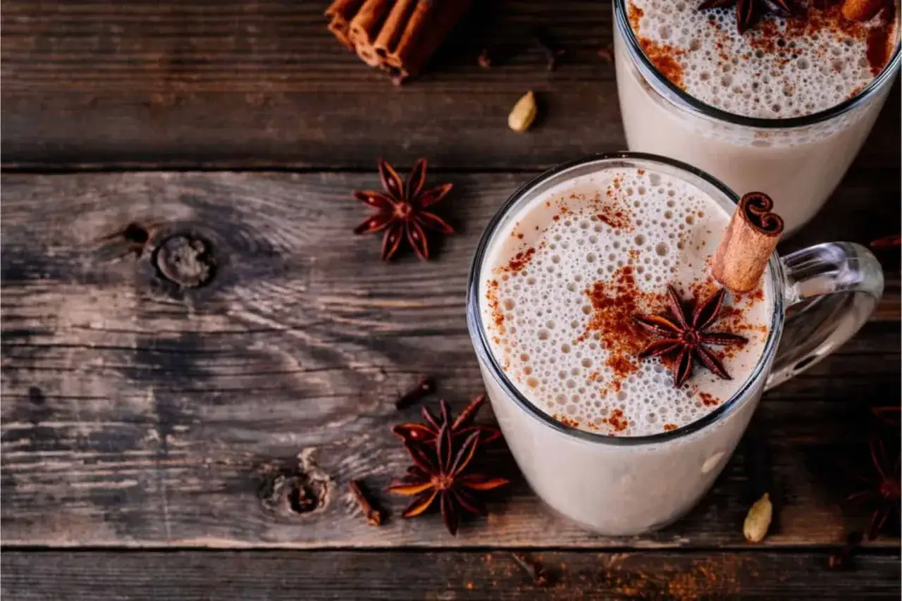 Zwei Tassen cremiger Chai Latte mit Zimt, Sternanis und Kardamom auf rustikalem Holz. Perfekt f&uuml;r die chai latte schwangerschaft.