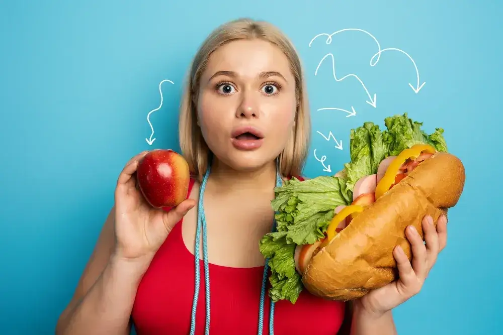 błędy w odchudzaniu, kobieta jedząca fast food po treningu