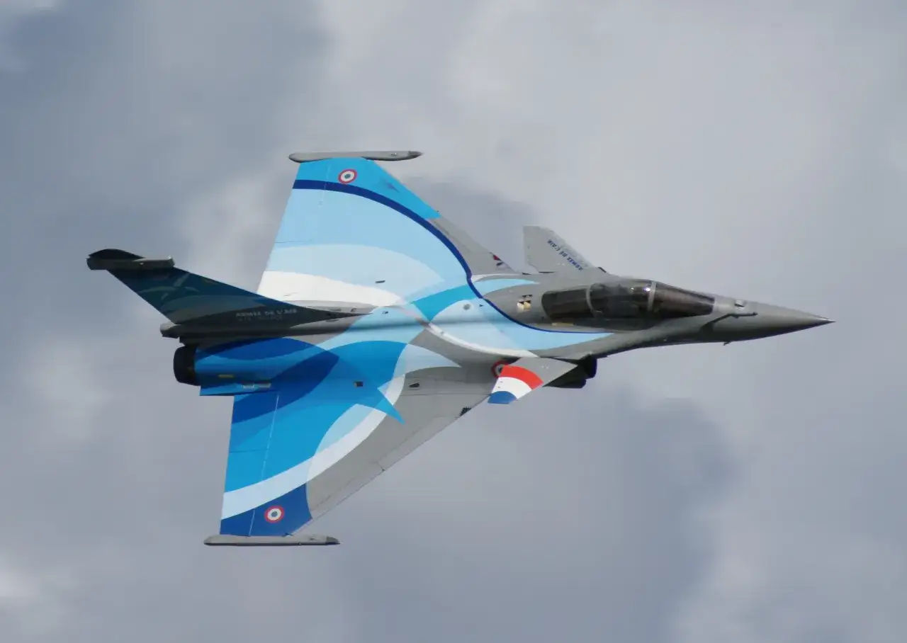 Francuski myśliwiec Rafale z błękitnymi falami na skrzydłach podczas pokazów lotniczych w Radomiu.