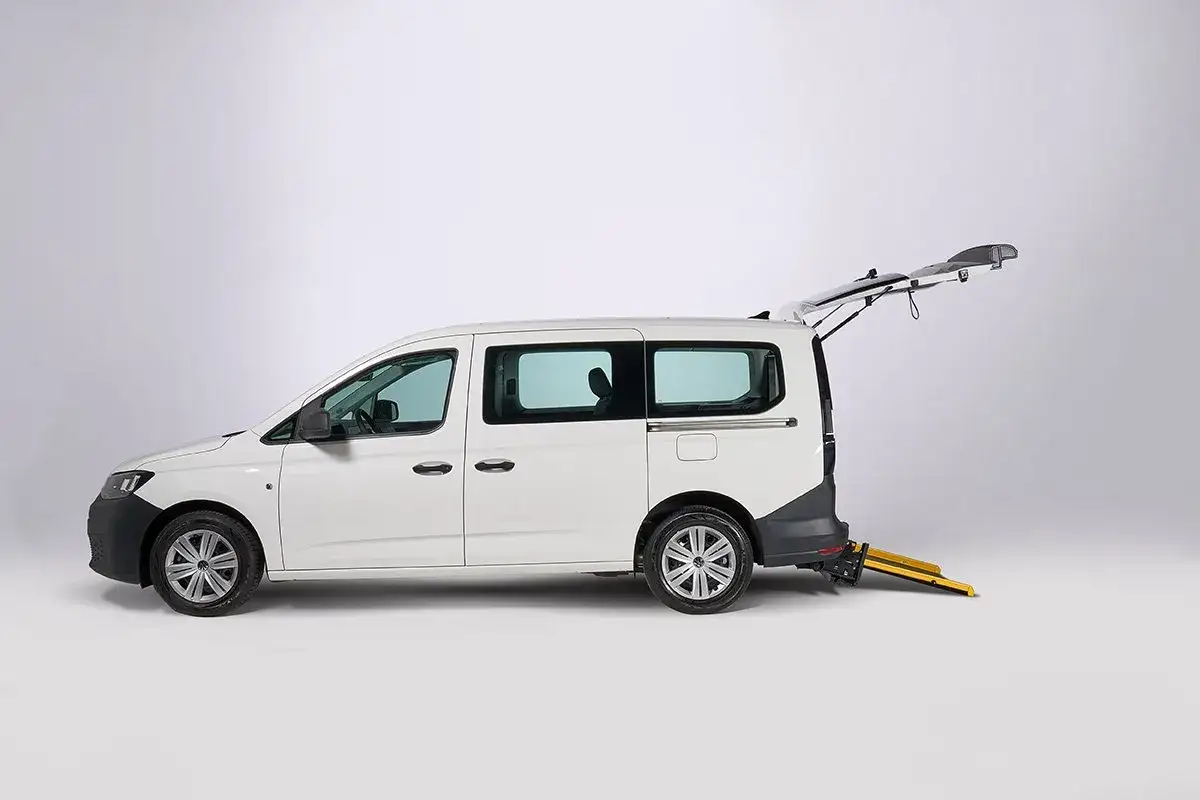 VW Caddy hybrid con rampa per sedie a rotelle estesa, pronto per l'accessibilità.