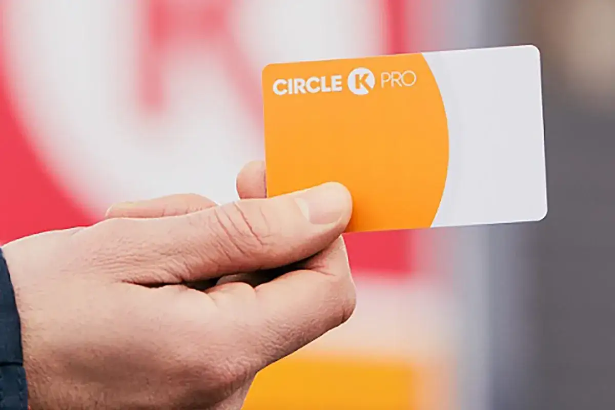 Dłoń trzyma pomarańczowo-białą kartę paliwową Circle K PRO.
