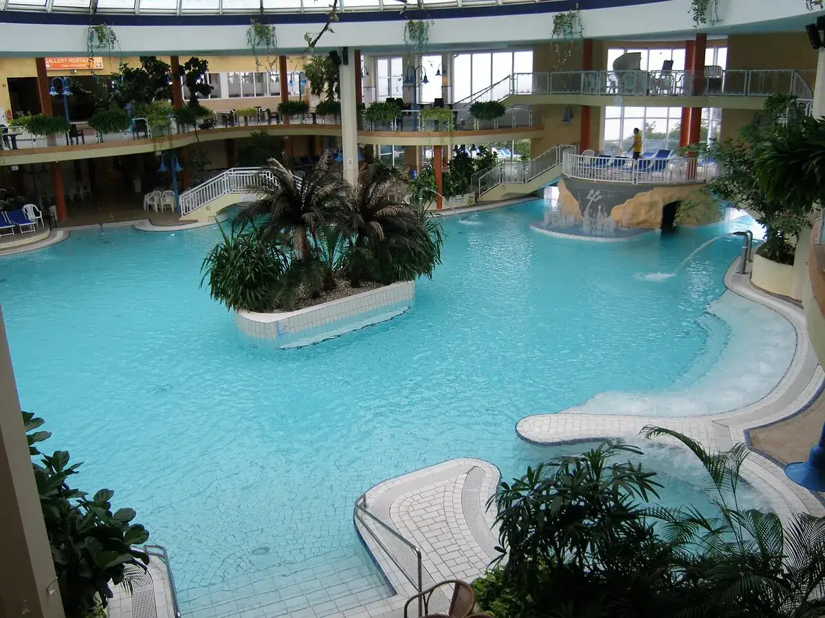 Großes Schwimmbad mit Palmen und Wasserrutschen, ideal für Ausflugsziele Ostsee bei schlechtem Wetter.