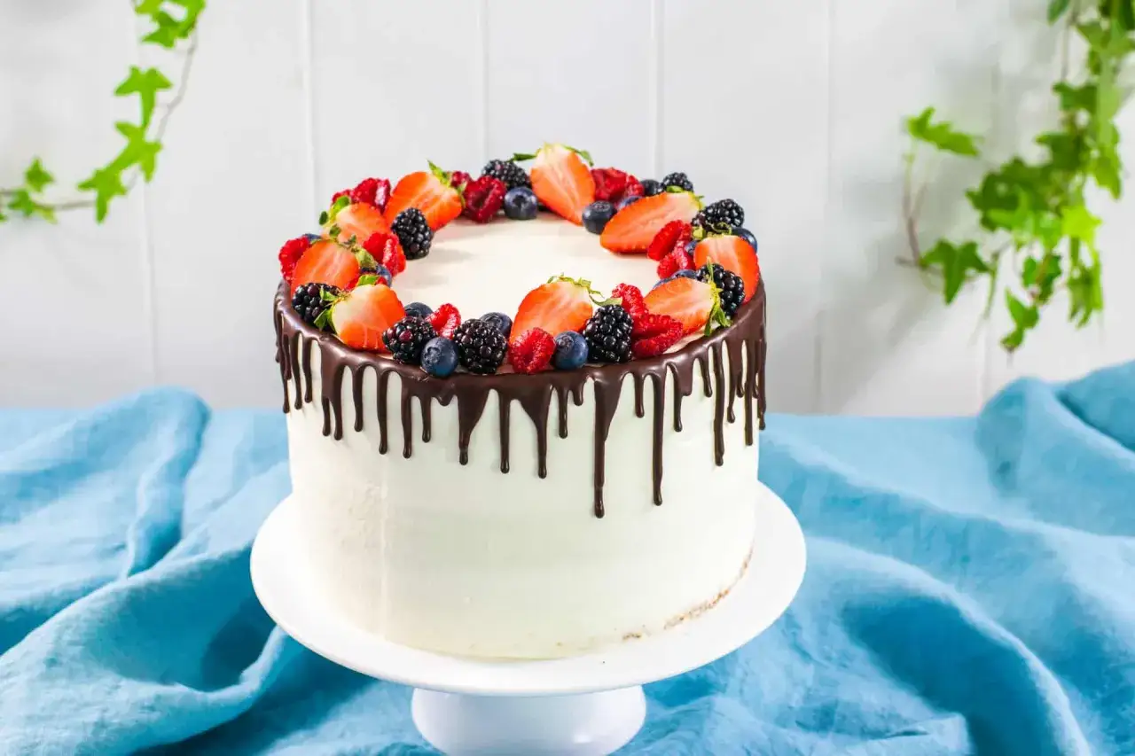 Torte di buon compleanno decorate con fragole, lamponi, mirtilli e more, con colature di cioccolato fondente.